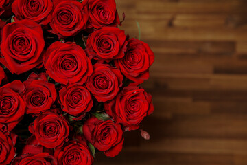 Beautiful red rose flower heads, photographed from above on brown wooden table. Spring flowers. Wedding, women's day, mothers day and valentines day background. Selective small depth of field.