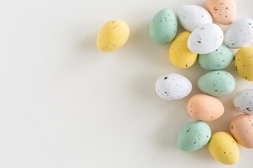 Chocolate easter egg in pastel colors on a white background, flat lay with copy space