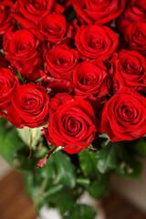 Beautiful red rose flower heads, photographed from above on brown wooden table. Spring flowers. Wedding, women's day, mothers day and valentines day background. Selective small depth of field.