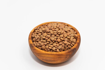 Raw brown lentil in a wooden bowl isolated on white background 