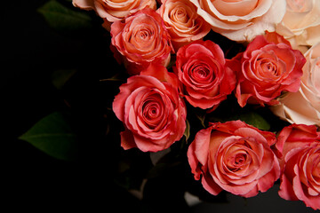 Beautiful white, red, tabby tea rose flowers in a vase, photographed from above on a black table. Spring flowers. Wedding, mother's day and valentines day background. Selective, small depth of field.