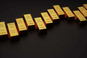 Gold bars next to each other on a black background. Shiny precious metal for investment or as a reserve. Place for text.