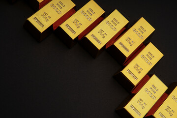 Gold bars next to each other on a black background. Shiny precious metal for investment or as a reserve. Place for text.