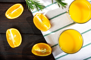 Orange slices on a dark wooden table. A glass of orange juice - top view. The process of making orange juice.