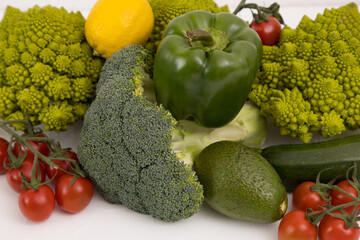Healthy vegetarian food, fresh green food, green vegetable, romanesco broccoli, pepper, zucchini, avocado, cherry tomato and lemon, on a isolated background