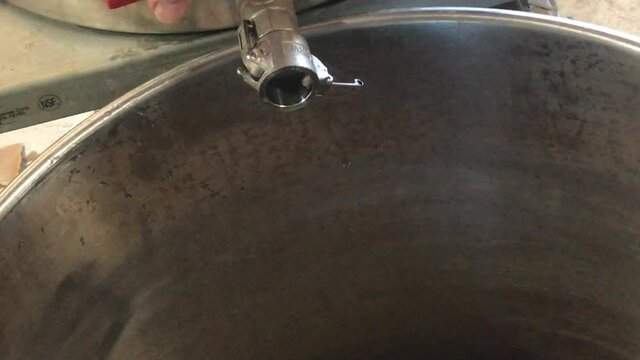 pouring hot steaming wort from mash tun into beer brew kettle