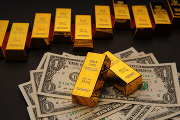 Shiny gold bars in a row and US dollar banknotes. Shiny precious metals for investments or...