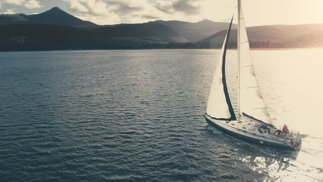 Sunrise over sailboat aerial. Sailing yacht in sun reflection at open sea. Mountain island at ocean bay. Nature seascape. Yachting sport. Marine vacation at coastal water. Cruise at Croatia on ship
