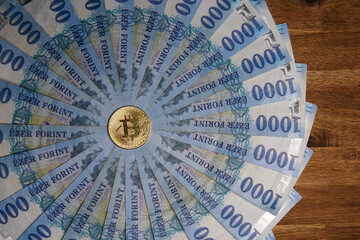 Pile of 1000 Hungarian forints, round. Multiple gold bitcoin digital cryptocurrency coins scattered. Bank image and photo background.