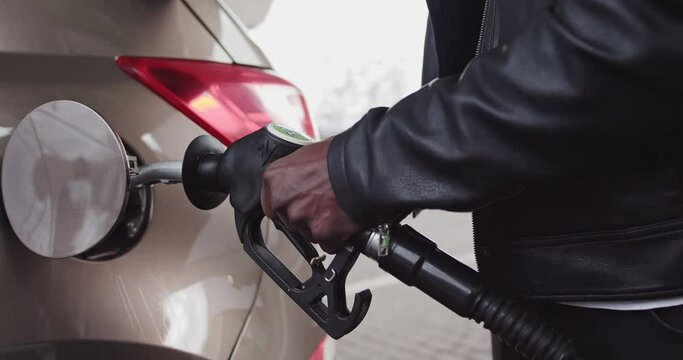 Closeup of man filling benzine gasoline fuel in car at gas station. African American Man Refueling Car At Gas Station. Fuel, gas station, petrol prices concept. Gasoline, gas, fuel, petroleum concept