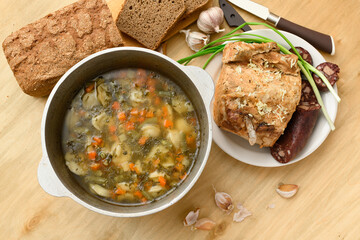 baked meat, soup and blood sausage on a plate, green onion and garlic on wooden background, home...