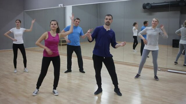 Portrait of dancing girl practicing vigorous swing during group training in dance studio