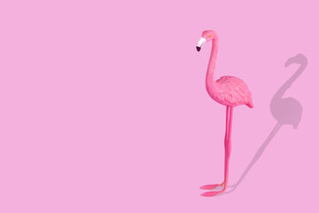 Pink flamingo figure with shadow on pastel pink background.