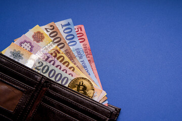 Several Hungarian forint paper money denominations, with gold bitcoin digital cryptocurrency coin on a blue background, in a wallet. Bank image and photo.