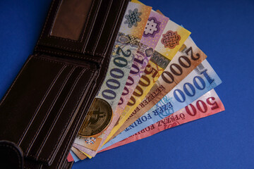 Several Hungarian forint paper money denominations, with gold bitcoin digital cryptocurrency coin on a blue background, in a wallet. Bank image and photo.