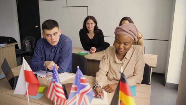 Foreign school private study with a school girl. Teacher explain grammar of native language using laptop. Prepearing to exam with tutor. English, British, German and Poland flags in front.