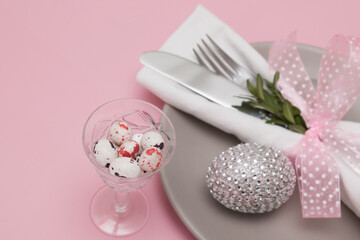 Glass with Easter eggs on the background of plates and cutlery. Variative focus
