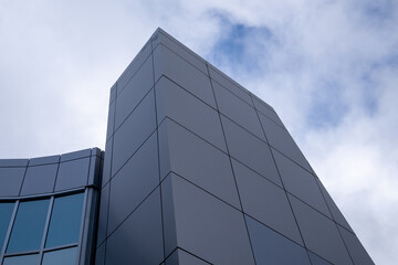 Plakat The exterior wall of a contemporary commercial style building with aluminum metal composite panels and glass windows. The futuristic building has engineered diagonal cladding steel frame panels. 