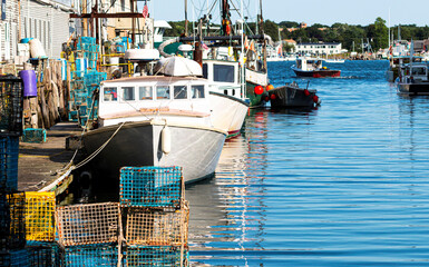 Lobster fishing boats docked in a canal with lobster traps pilled on the dock in Portland Maine