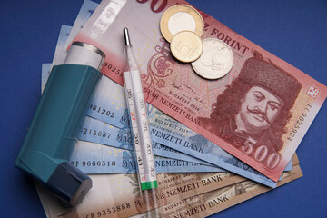 Asthma medicine thermometer and money for medical treatment. Hungarian paper money forint. Asthma inhaler, pipe.