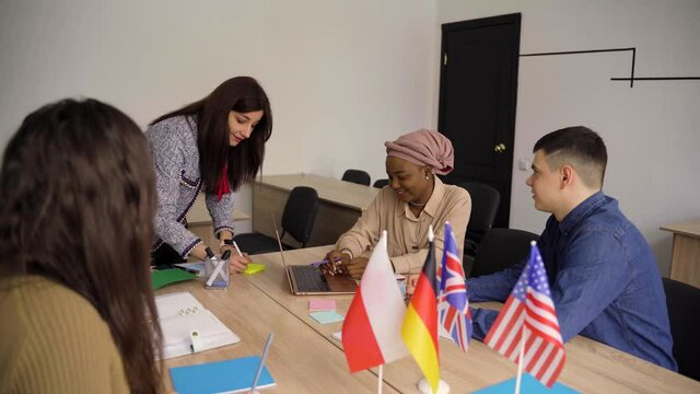 Teamwork. Working in multiethnic group of students. teacher study foreign languages together in class. Studing with laptop. Black handsome girl student study with white people together