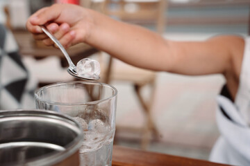 Little girl with mom playing with ice cubes in a cozy cafe.