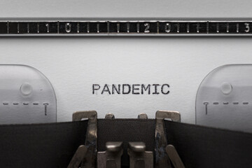 Typing text PANDEMIC on vintage manual typewriter. Close up of writes word on white paper. Shot in...