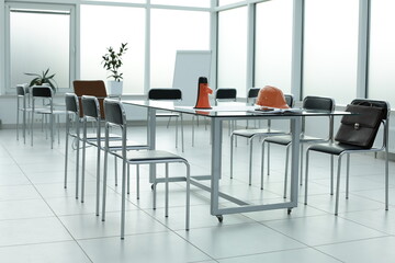 Fototapeta premium Loudspeaker construction helmet chairs diary briefcase phone glass table in a bright office