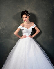 Fototapeta premium Attractive young model in a white dress with jewelry in her hair. Beautiful bride with wedding makeup and fashion hairstyle