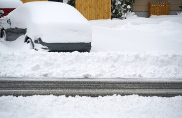Close up on residential street after snow with parked car buried in snow