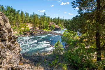 The huge boulders along the Spokane River and the wooden suspension bridge at Bowl and Pitcher inside the Riverside State Park in Spokane Washington, USA