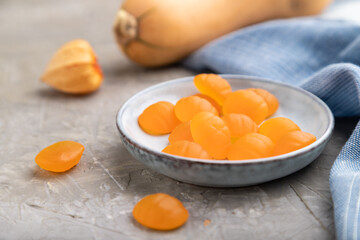 Jelly pumpkin candies on gray concrete background. close up, side view, selective focus.