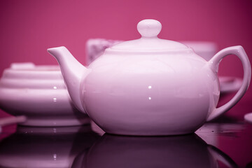 A porcelain teapot with cups is on the table in the restaurant. Purple ceramic tableware. The concept of tea drinking.