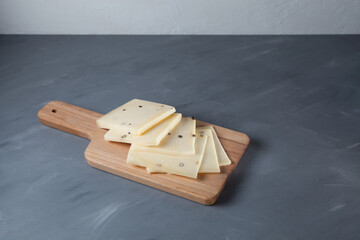 Italian Caciotta cheese with black pepper. Slices lies on wooden cutting board