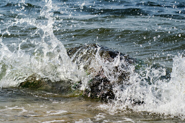 Fototapeta Sea wave hitting the rocky shore. Falling water drops  obraz
