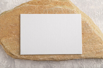 White paper business card, mockup with stone on gray concrete background. flat lay, canvas, copy space.