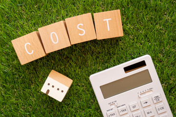 コスト | 「COST」と書かれた積み木ブロックと家のおもちゃと電卓