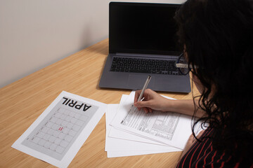 Obraz premium Session to set up bills and bills for tax day at a table with a calculator and a laptop with a spreadsheet