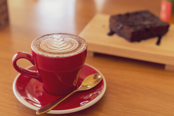 Close up hot cappuccino, latte, caramel macchiato on table with blur coffee shop background. Process with warm vintage tone style.