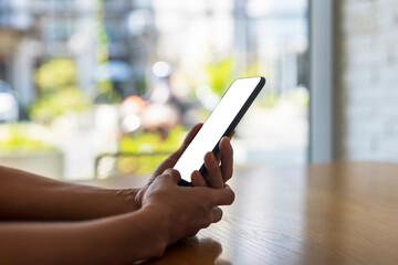 Close up hands of beautiful young woman holding mobile, smart phone sitting in cafe. Soft focus hands of women holding and use cell phone in coffee shop. Tech Technology and lifestyle concept.