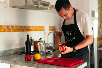 A man cuts apples on a wooden board to prepare grilled wine.