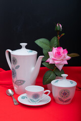 Breakfast service with a cup of coffee, coffee or tea, sugar bowl and vase with pink flowers.
