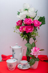 Breakfast service with a cup of coffee, coffee or tea, sugar bowl and vase with pink flowers.
