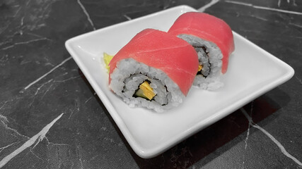 Sushi roll (Maguro) with tuna, cucumber, egg, seaweed and rice, serving on white plate. Traditional Japanese food