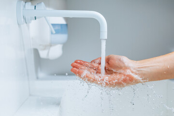 hand under the faucet with flowing water splash