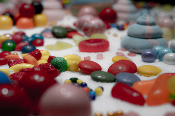 Chocolate coated and jelly beans candy mix view, shallow depth of field. Festive dessert of different kinds of soft gummy, lollipop for holiday. Slow rotation of big explosion. Macro.
