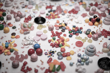 Candy in variety of colour, shape, size and flavours mixed on the table with real white sugar. International Candy Day background. Sweet stock of snack, chocolates, caramels, candy, and jelly beans.