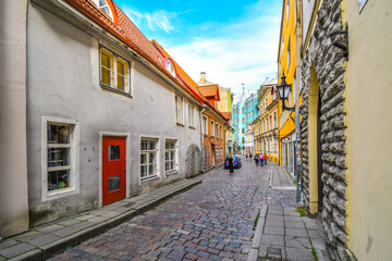Tourists walk down a picturesque cobblestone street in a residential and business area of the...