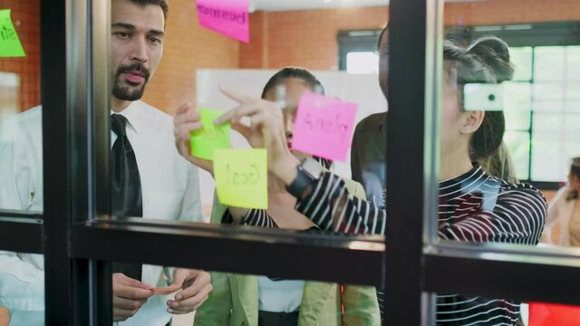 Group of business people sharing idea, putting sticky note on the wall