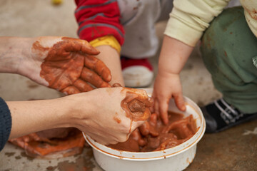 Woman squeezes the clay before molding figures together with children